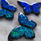 Three butterfly shaped epoxy resin pieces made with blue glitter and black vinyl details, displayed on a white background.