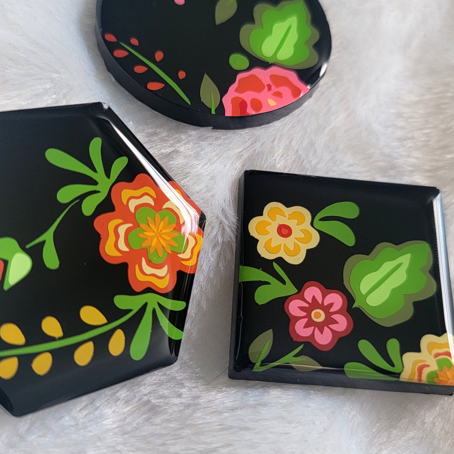 Three black epoxy resin pieces with vibrant green, pink, and orange floral designs.