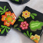 Three black epoxy resin pieces with vibrant green, pink, and orange floral designs.
