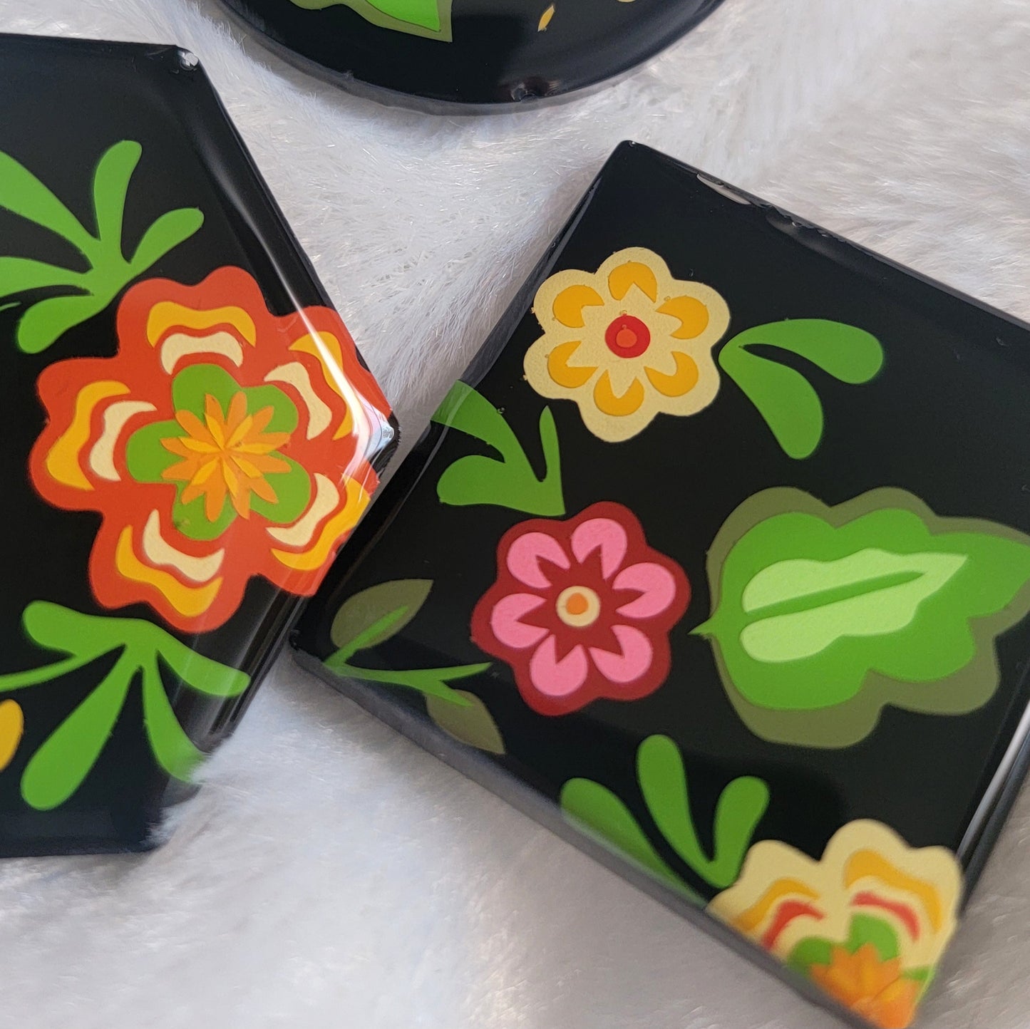 Three black epoxy resin pieces with vibrant green, pink, and orange floral designs.