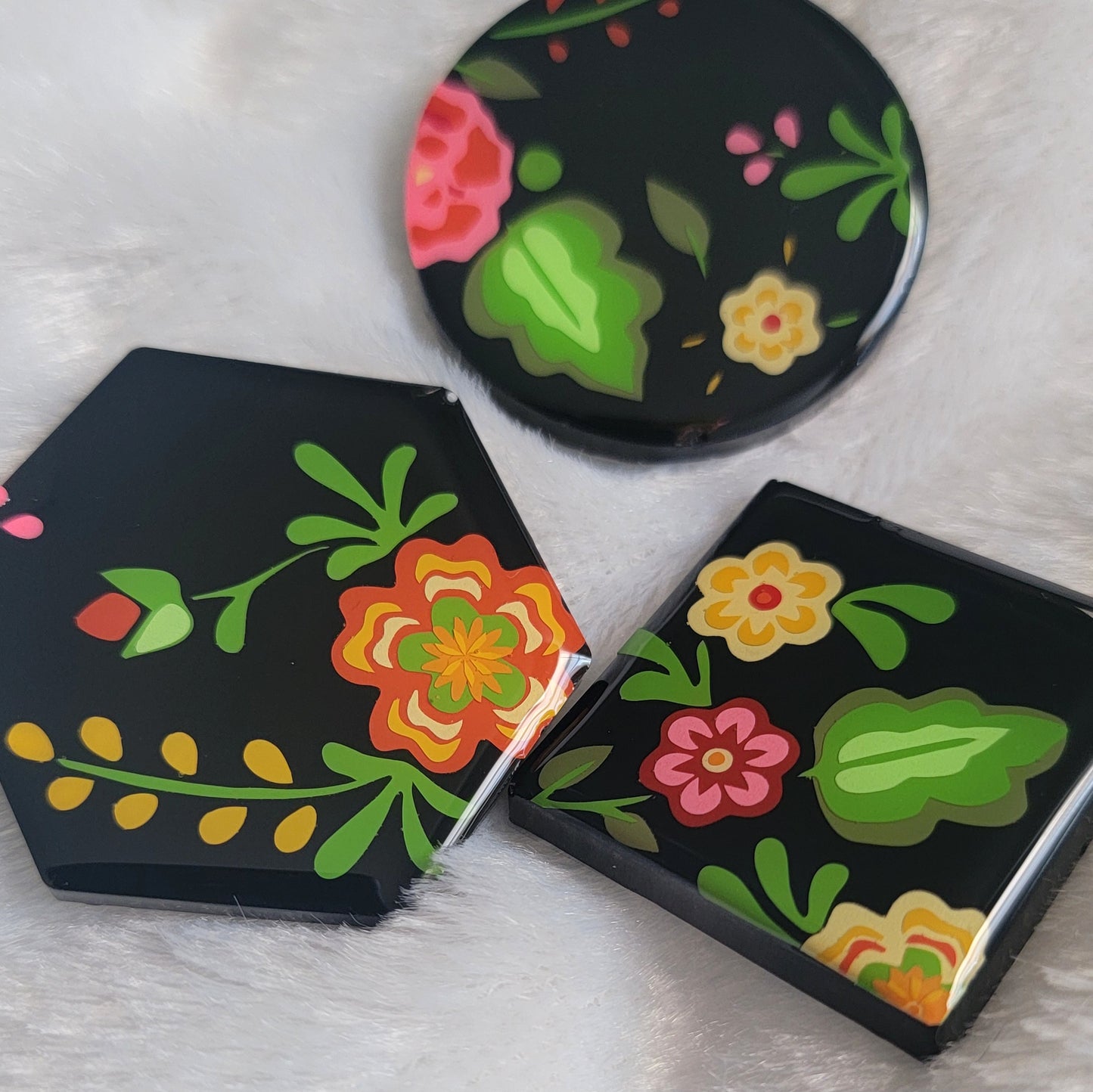 Three black epoxy resin pieces with vibrant green, pink, and orange floral designs.