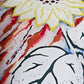 Close up of sunflower art made with yellow, green and brown vinyl, with rust and navy blue acrylic abstract painted background on white; accented with gold glitter and sealed in epoxy resin.