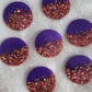 Seven round epoxy resin pieces, each one made half-and-half with violet pigment and rosey pink holographic glitter.