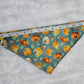 Bandana shown with measuring tape to show small size is 15.5", print is pumpkins on dusty blue background.