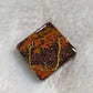 Square epoxy resin piece with fall trees scene made of gold colored jewelry wire and holographic orange leaf shaped glitter.
