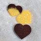 Three heart shaped epoxy resin pieces, one dark red glitter, one bright yellow glitter, and one a combination of the dark red and bright yellow glitters.