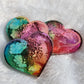 Three heart shaped epoxy resin pieces made with multicolored alcohol inks.